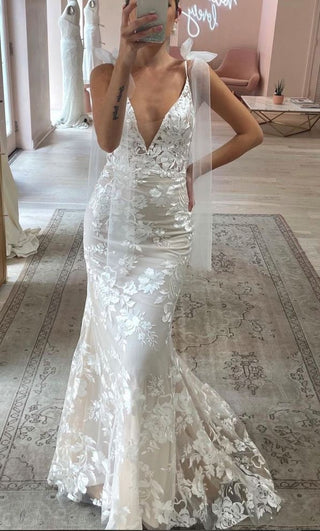 Elegant ivory lace wedding gown with a deep plunging neckline, floral embroidery, and a fit-and-flare silhouette, perfect for modern and romantic bridal styles