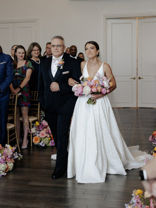 Elegant ivory bridal dress featuring a deep V-neckline, sleeveless design, and a classic A-line silhouette with a subtle train, ideal for timeless and sophisticated weddings