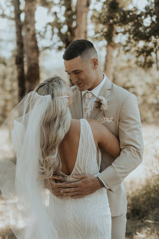 Reflection of a bride in a mirror, showcasing her stunning lace wedding dress and radiant smile