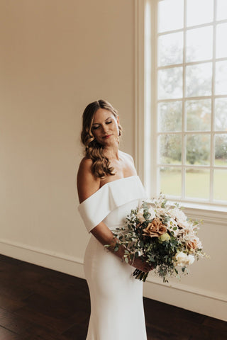 Sophisticated strapless white wedding dress, clean lines with subtle ruffle accent at the neckline, paired with a romantic pearl-embellished veil, perfect for understated bridal elegance