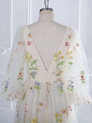 Vintage-inspired cream dress with vibrant wildflower patterns, a cinched waist, and flowing layered skirt, ideal for garden weddings or bohemian events.