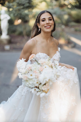 Sophisticated ivory A-line wedding dress with floral lace embroidery, sweetheart neckline, flowy tulle skirt, and delicate spaghetti straps, designed for boho and fairytale-inspired weddings