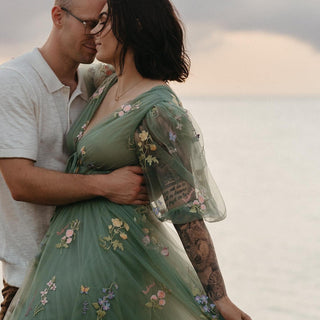 Charming floor-length green dress with floral detailing, sheer bishop sleeves, and a cinched waist, creating a graceful and ethereal look, ideal for outdoor family portraits or formal occasions