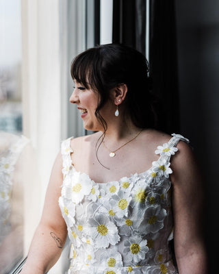 Romantic ivory ball gown adorned with yellow daisy embroidery and sheer tulle layers, perfect for enchanting garden-themed weddings or whimsical bridal occasions