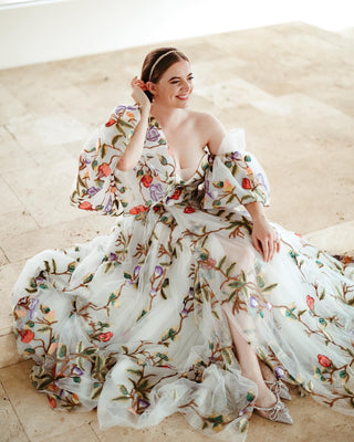 Ivory A-line gown with colourful floral embroidery, sheer puff sleeves, and a sweetheart neckline, perfect for whimsical weddings and romantic garden-themed celebrations