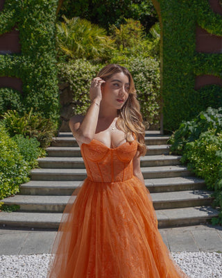 Vibrant orange tulle gown featuring intricate floral lace embroidery, a structured corset bodice, and a flowing A-line silhouette, perfect for bold and elegant events