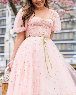 Light pink tulle midi dress with delicate white daisy embroidery, puff sleeves, a fitted bodice, and a green ribbon belt, perfect for whimsical spring garden parties and celebrations