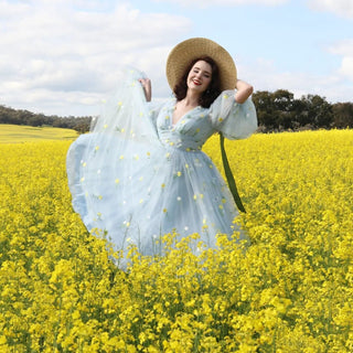 Romantic pastel blue A-line dress with intricate daisy embroidery, tulle puff sleeves, and a tea-length design, perfect for garden-themed weddings or bohemian parties