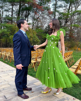 Romantic daisy-embellished green dress featuring soft tulle layers, a ruffle-trimmed neckline, and a flowing silhouette, designed for playful spring events or nature-inspired celebrations