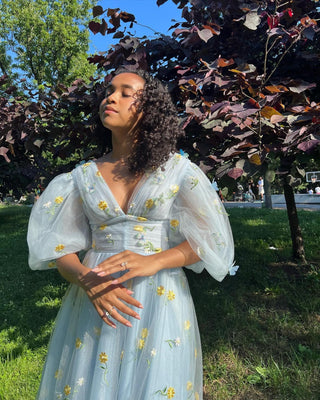 Chic blue midi dress adorned with yellow floral embroidery, sheer tulle layers, and voluminous puff sleeves, tailored for nature-inspired and whimsical events