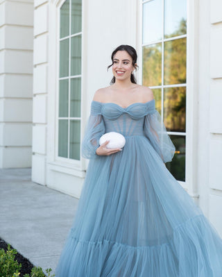 This exquisite dusty blue gown features a sophisticated off-the-shoulder design, enhancing the elegance and timeless beauty of the dress. The soft, flowing tulle creates an ethereal effect, perfect for a modern yet romantic aesthetic. The delicate off-shoulder neckline is complemented by sheer, billowing sleeves that add an extra layer of sophistication, making it a perfect choice for a formal event or evening occasion.