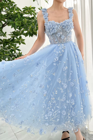 Chic pastel blue evening dress with hand-applied flowers and shimmering silver thread, square neckline with floral straps, and a flowing skirt, ideal for enchanting occasions or outdoor ceremonies