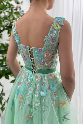 Charming green cocktail dress adorned with colourful flower appliqués and a fitted bodice, ideal for special occasions